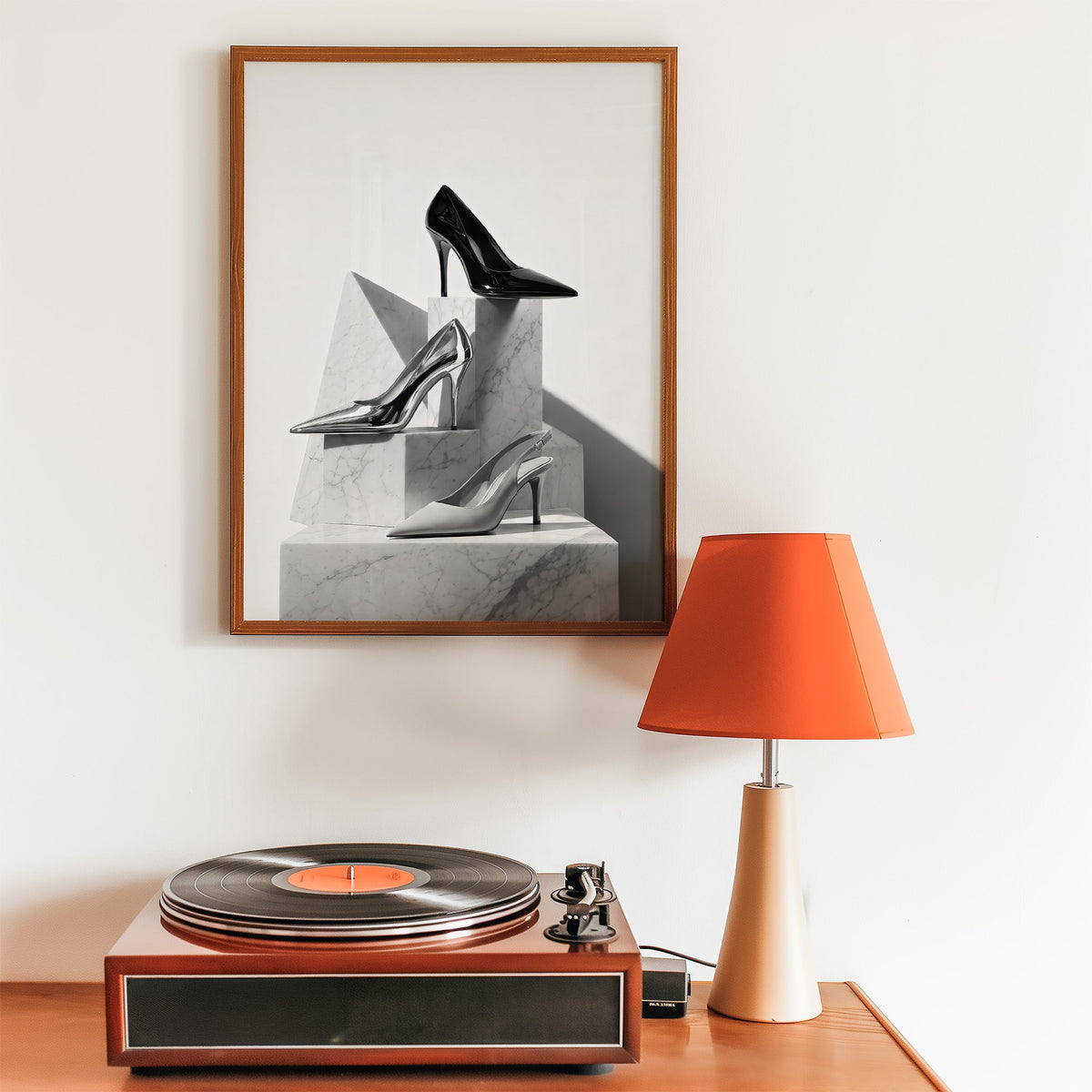Three pairs of heels on marble pedestals print in a walnut frame above a record player and orange lamp
