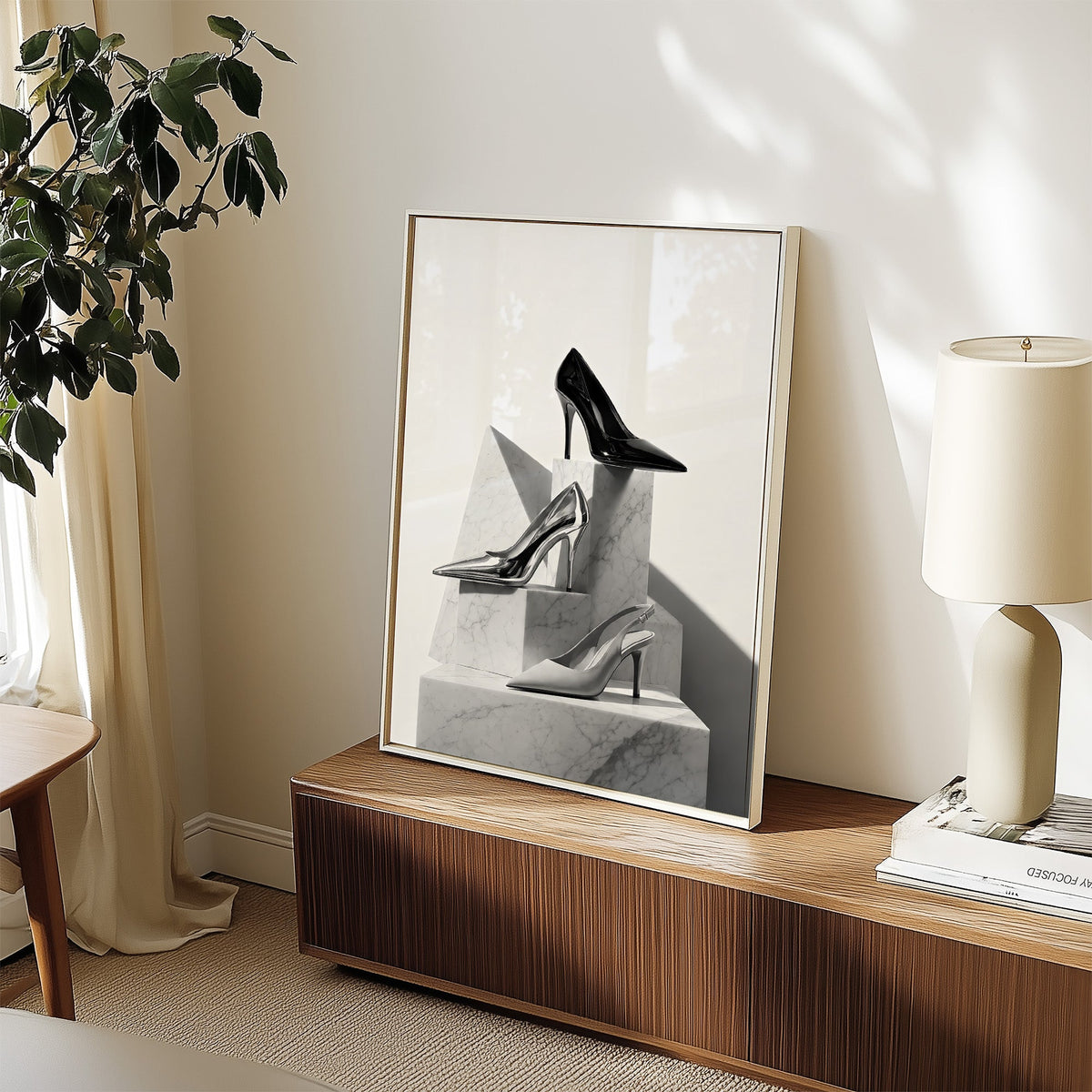 Three pairs of heels on marble pedestals print in a white frame on a walnut sideboard beside a ceramic lamp