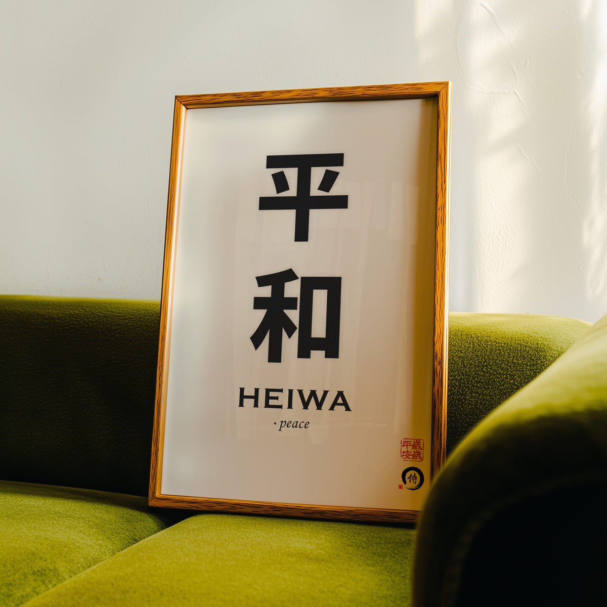 Heiwa peace kanji calligraphy print in an oak frame propped on a green velvet sofa