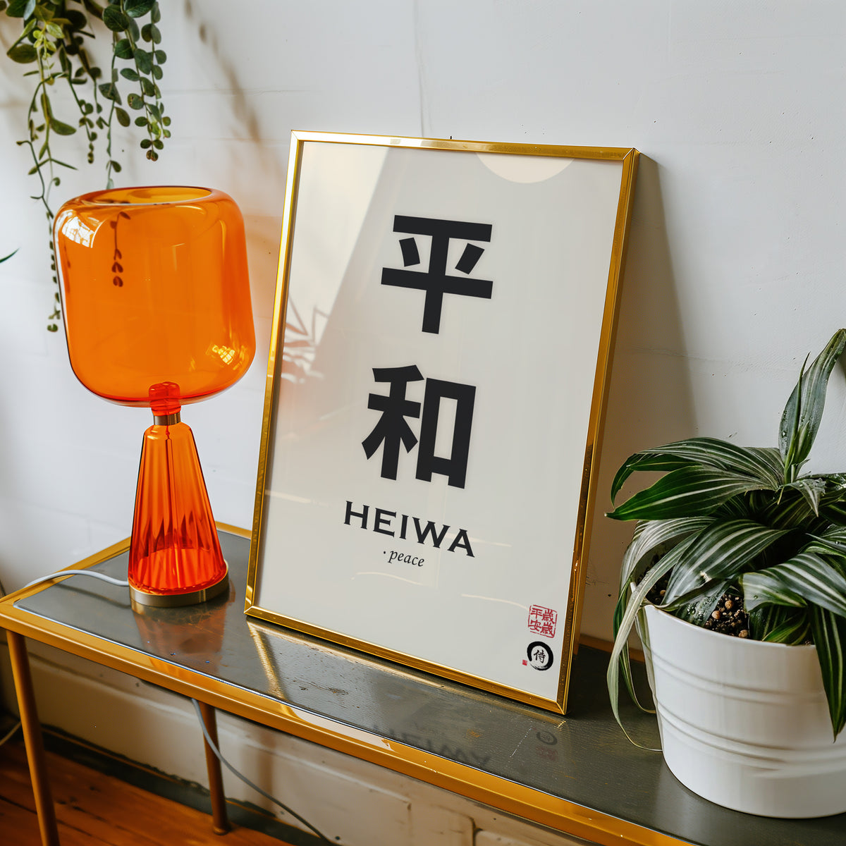 Heiwa peace kanji calligraphy print shown in a gold frame on a console beside an orange glass lamp
