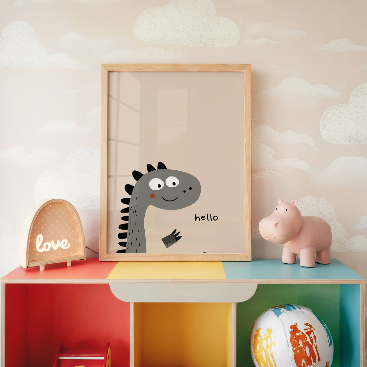 Hello peeking dinosaur nursery print in an oak frame on a rainbow toy shelf against cloud wallpaper