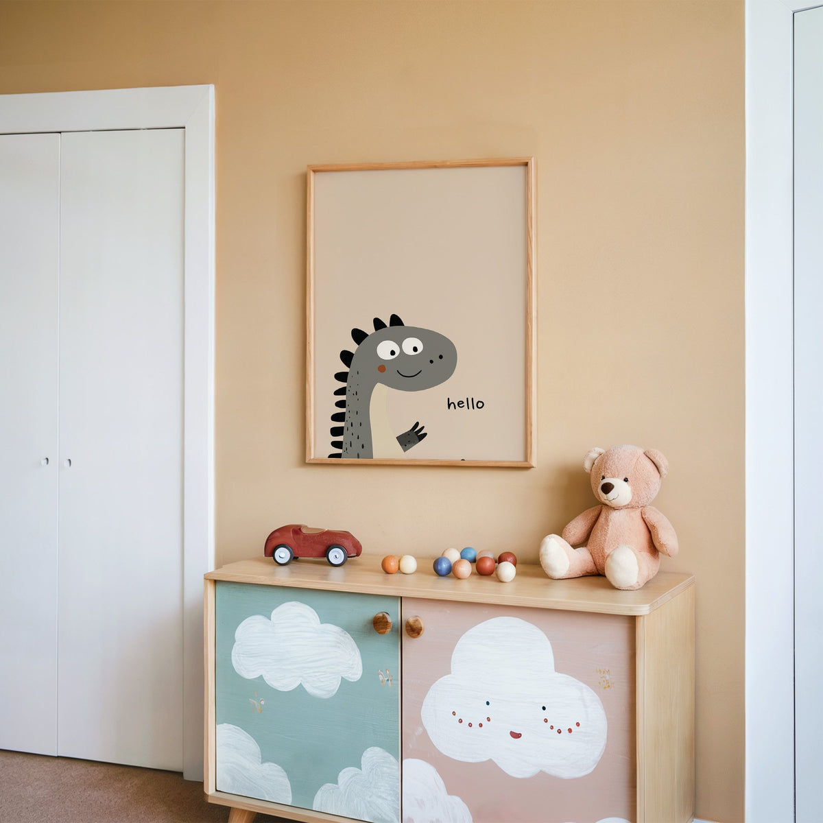 Hello peeking dinosaur nursery print in an oak frame on a peach wall above a cloud-painted cabinet