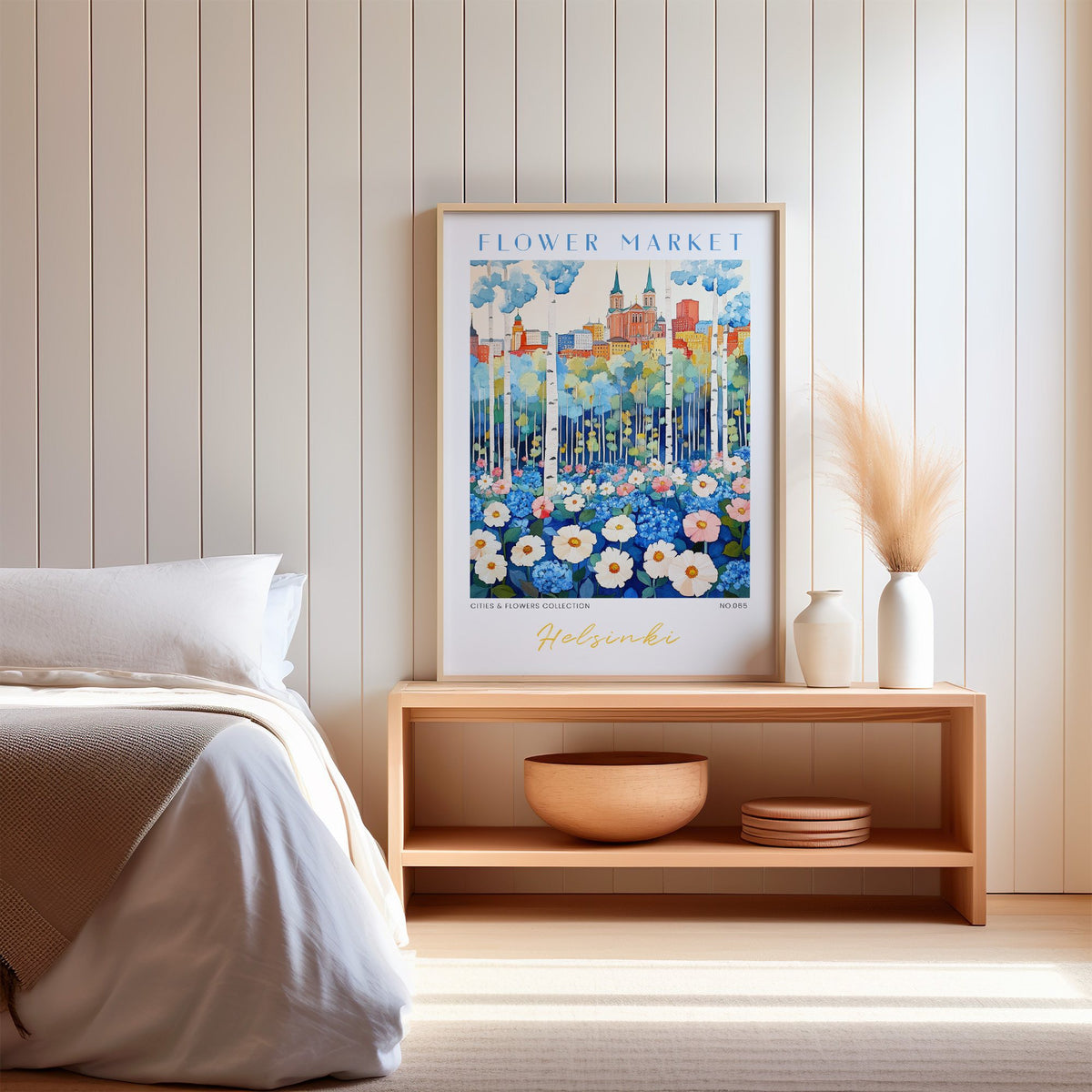 Helsinki flower market print in an oak frame on a wood bench against a white shiplap bedroom wall with pampas grass