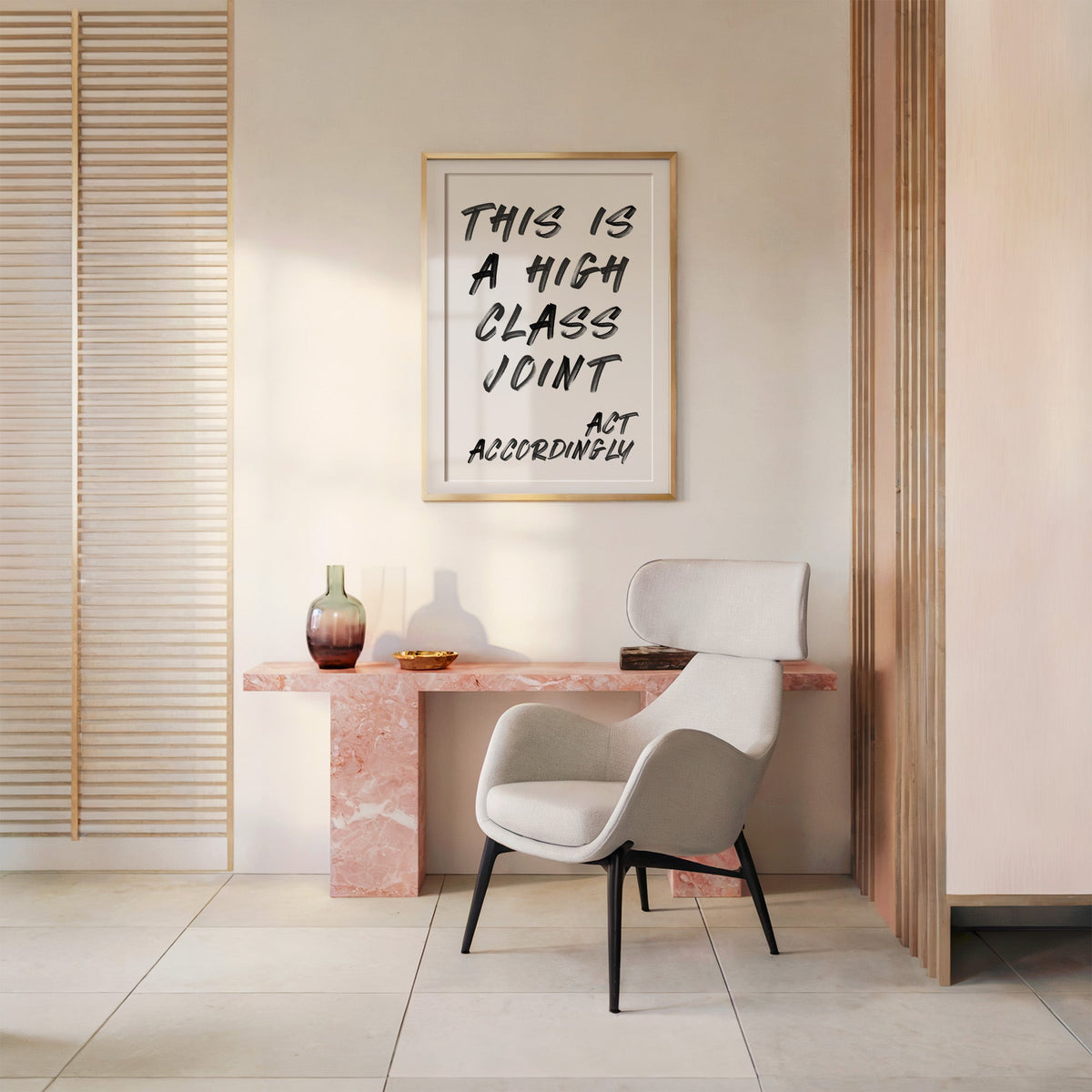 This is a high class joint brush quote print shown in a gold frame above a pink marble console and armchair