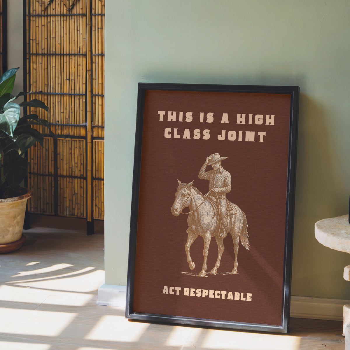 High Class Joint print in a black frame leaning against a sage green wall