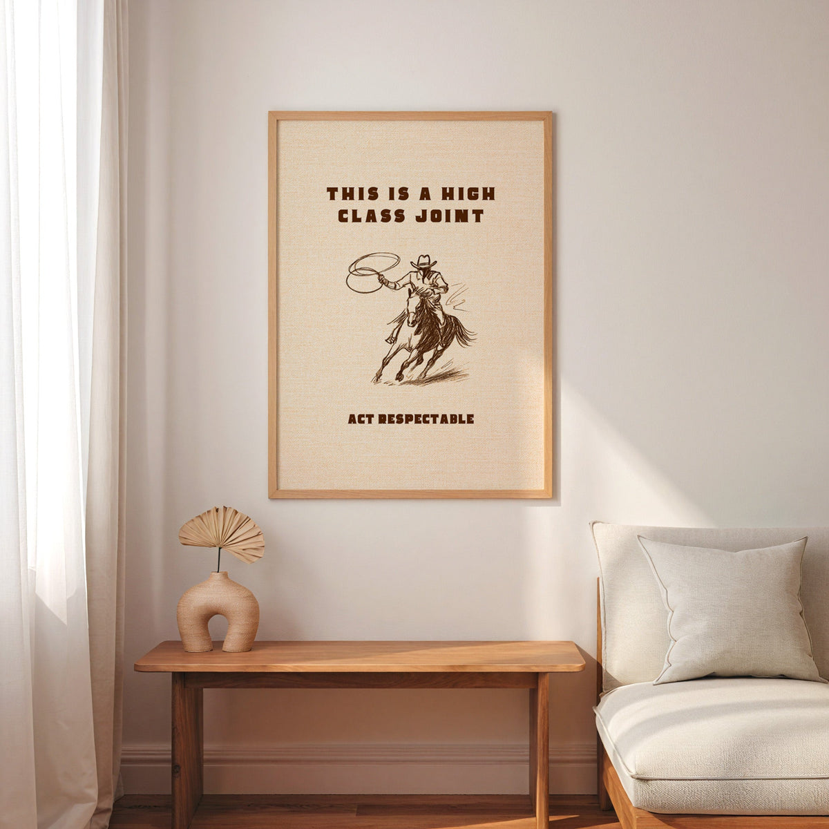 High Class Joint cowgirl cream print in an oak frame above a console with an arch vase