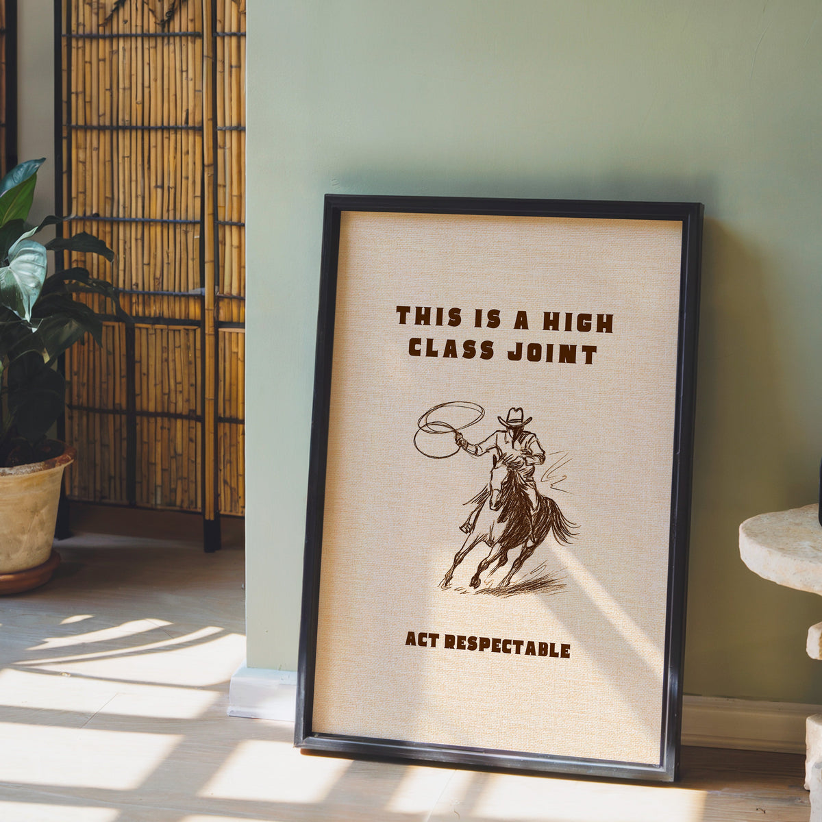 High Class Joint cowgirl cream print in a black frame leaning against a sage green wall