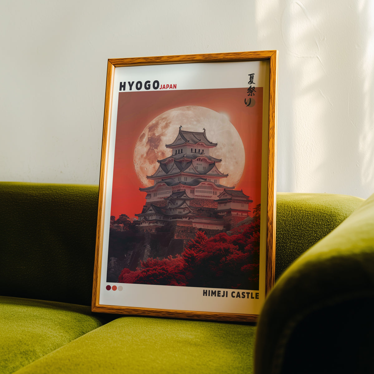 Himeji Castle red moon print in an oak frame propped on a green velvet sofa