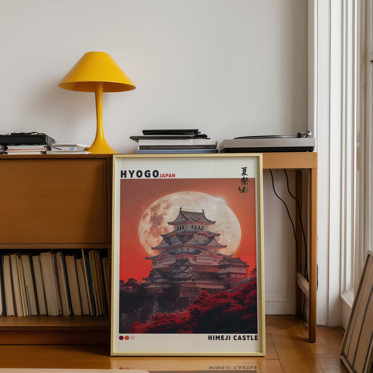 Himeji Castle red moon print shown in a gold frame below a teak desk with a yellow lamp