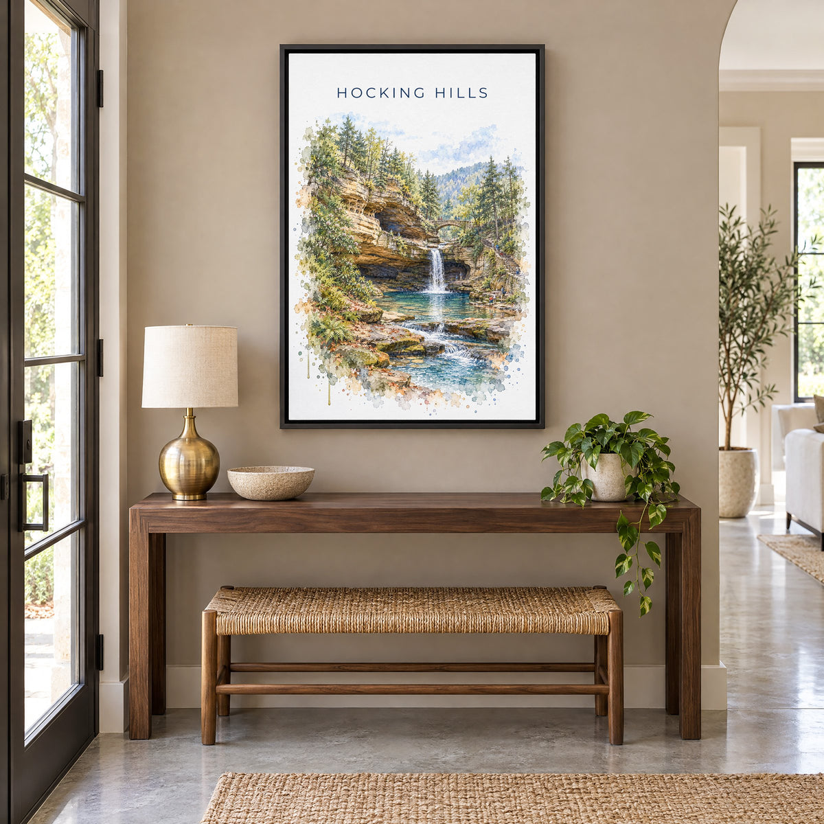 Hocking Hills watercolor print as a black floater canvas above a walnut console and woven bench in an entryway