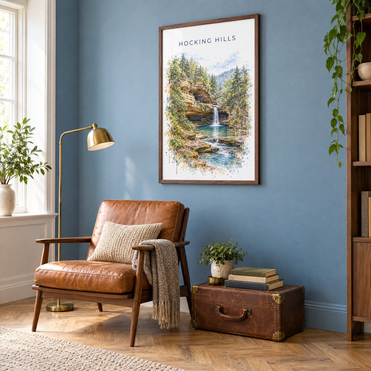 Hocking Hills watercolor print in a walnut frame on a blue wall above a leather armchair in a reading nook
