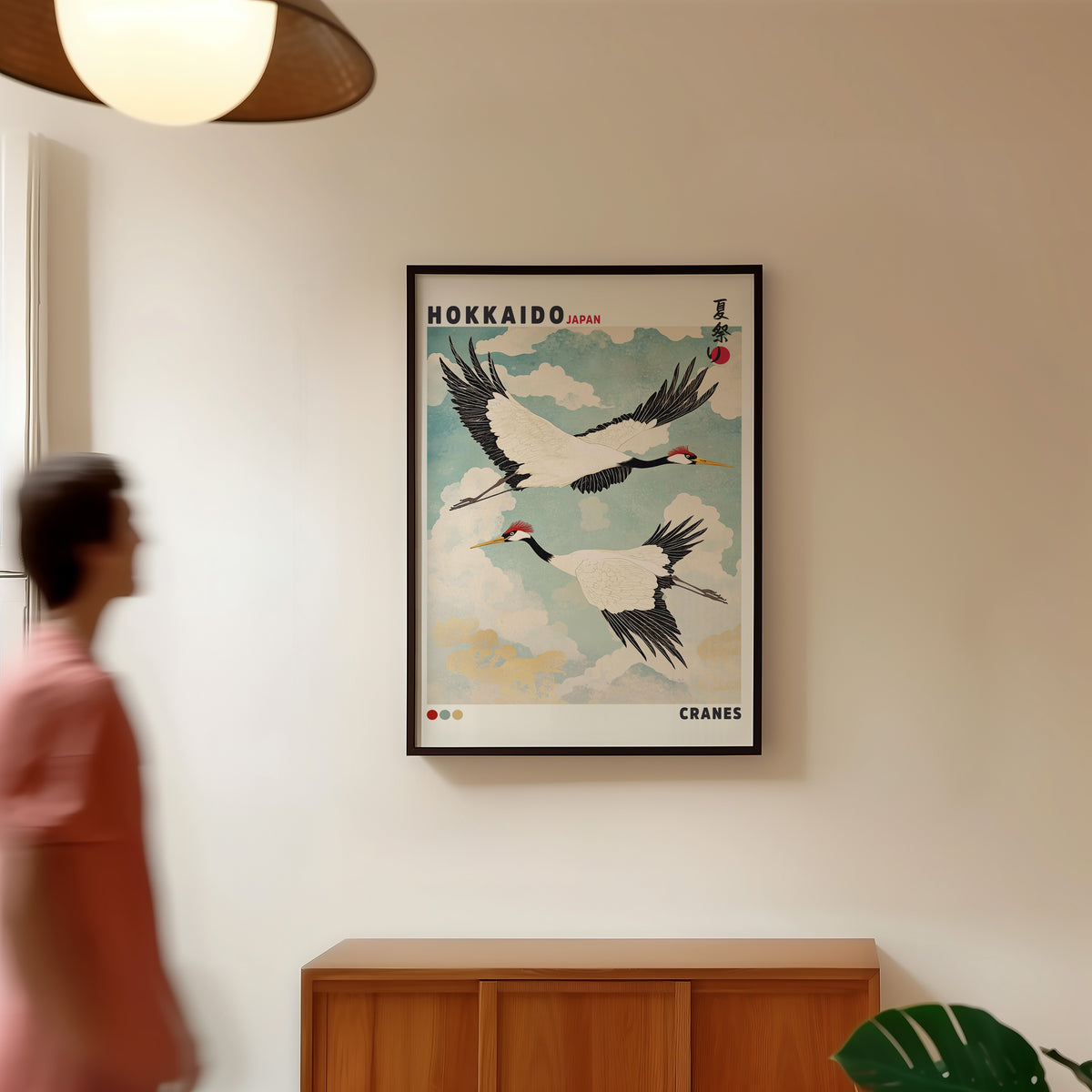 Hokkaido red-crowned cranes in flight print in a black frame in a hallway under a rattan pendant