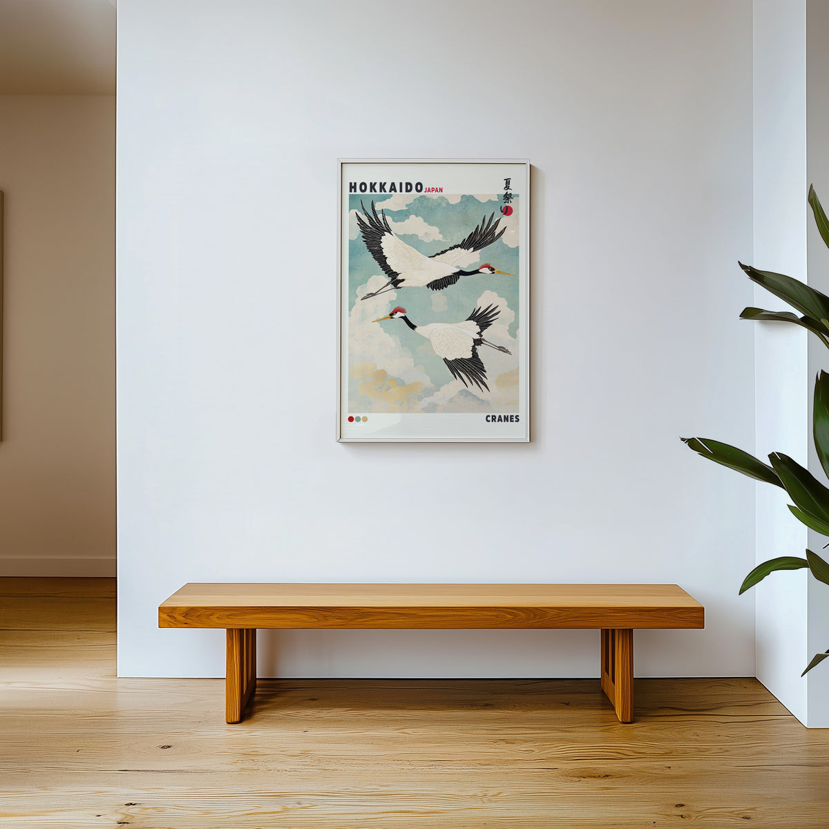 Hokkaido red-crowned cranes in flight print shown in a white frame above a wooden entryway bench