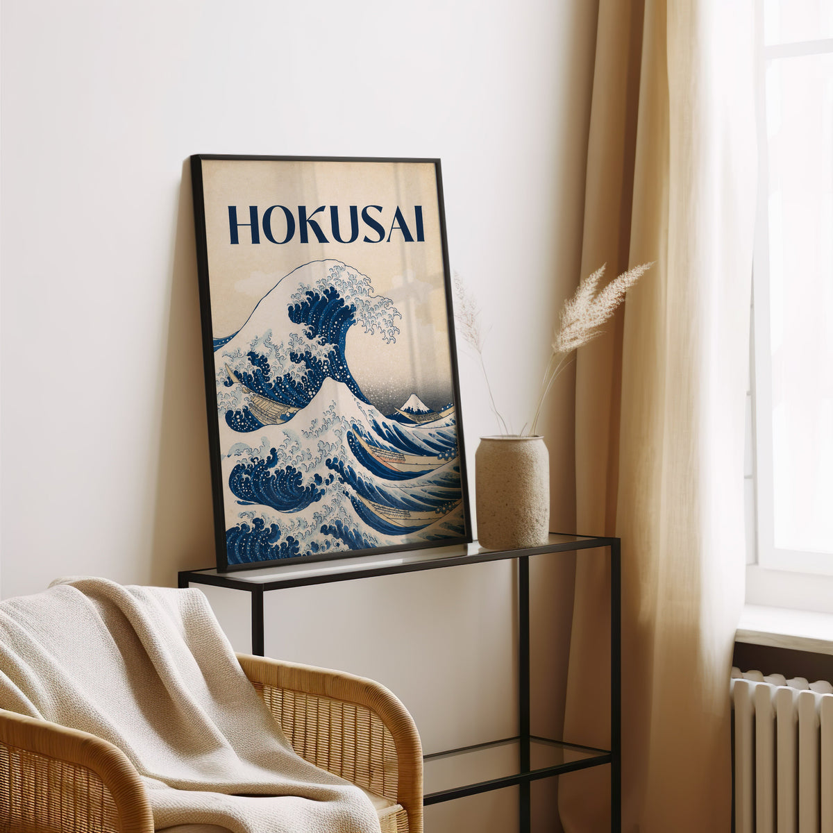 Great Wave with HOKUSAI title print in a black frame leaning on a glass console beside pampas grass