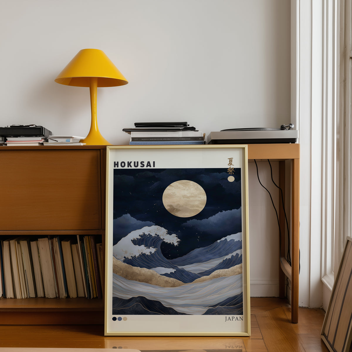 Hokusai night wave gold moon print shown in a gold frame below a teak desk with a yellow lamp