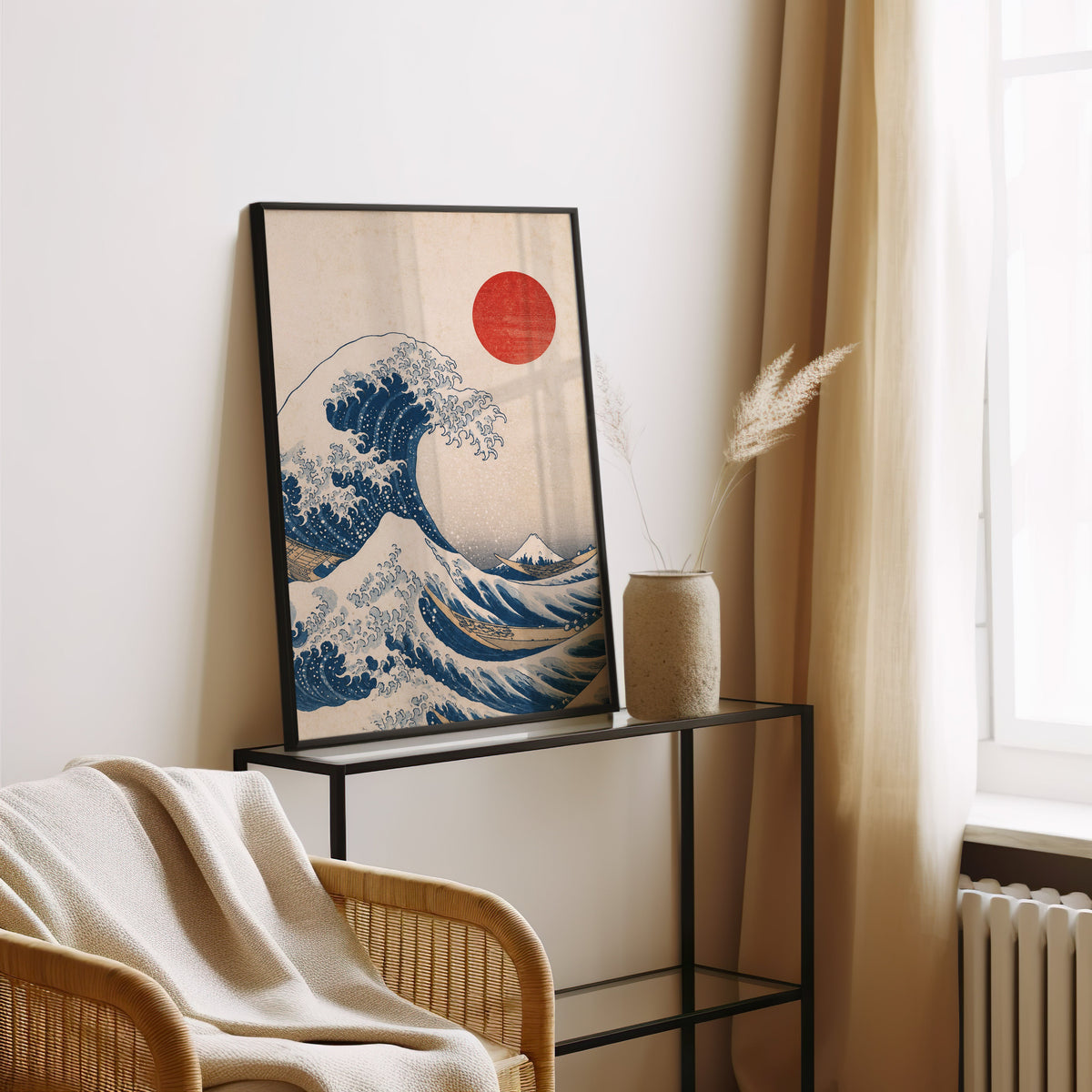 Great Wave with red sun print in a black frame leaning on a glass console beside pampas grass