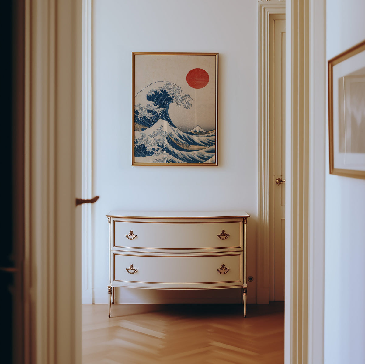Great Wave with red sun print shown in a gold frame in a hallway above a cream dresser