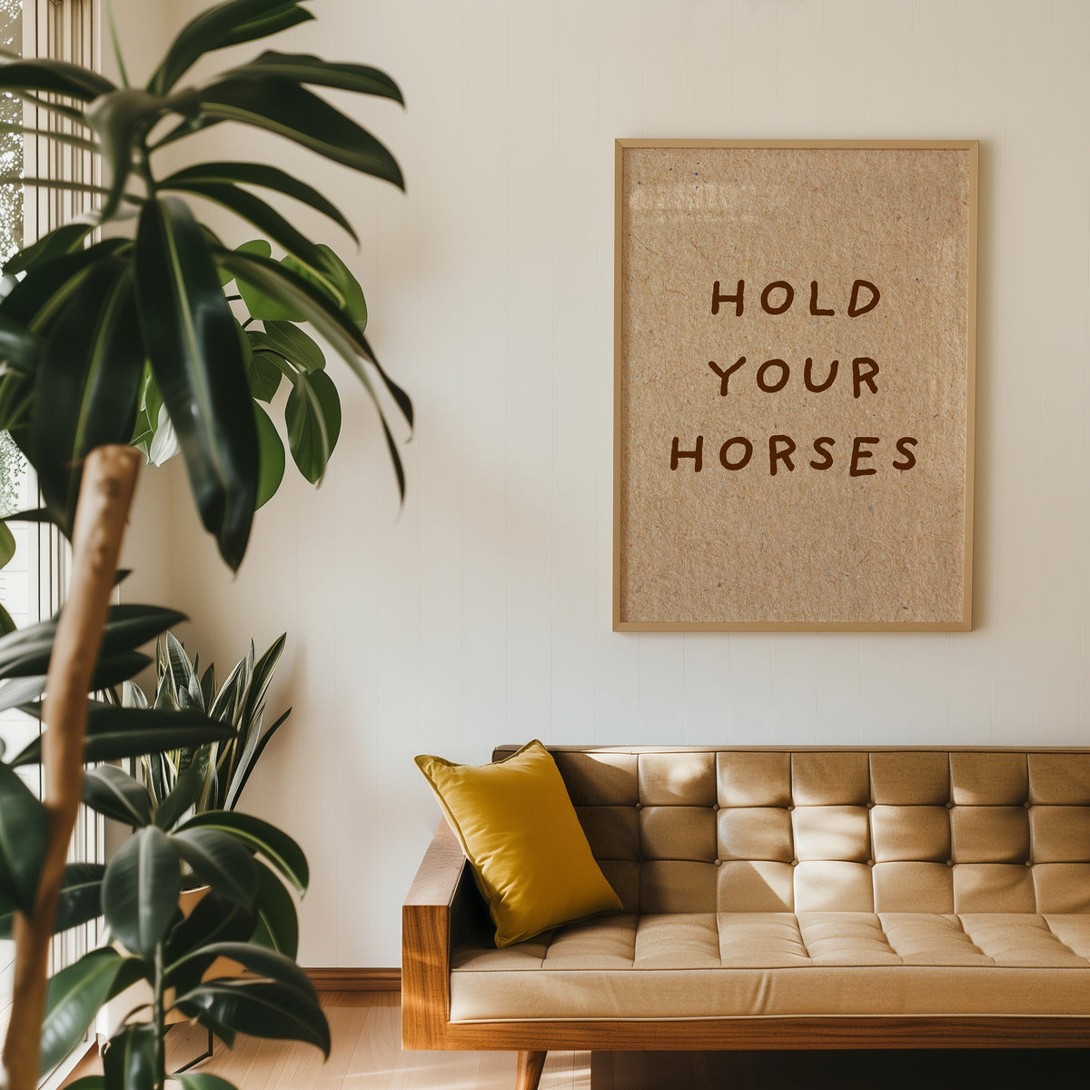 Hold Your Horses quote print in an oak frame above a tan leather sofa
