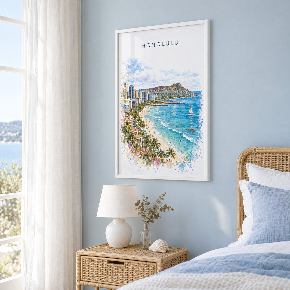 Honolulu watercolor print in a white frame on a pale blue wall beside a rattan bed in a coastal bedroom