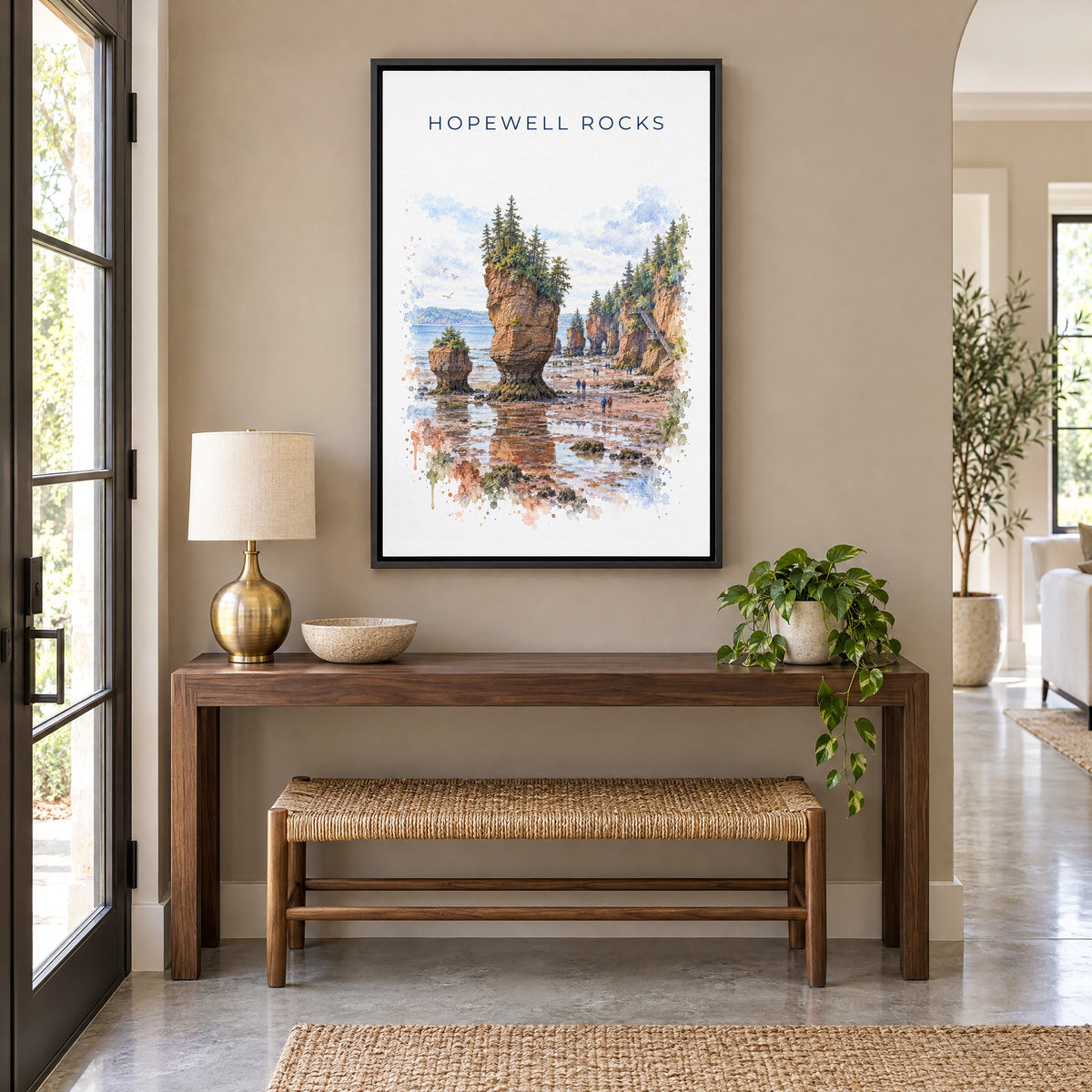 Hopewell Rocks watercolor print as a black floater canvas above a walnut console and woven bench in an entryway