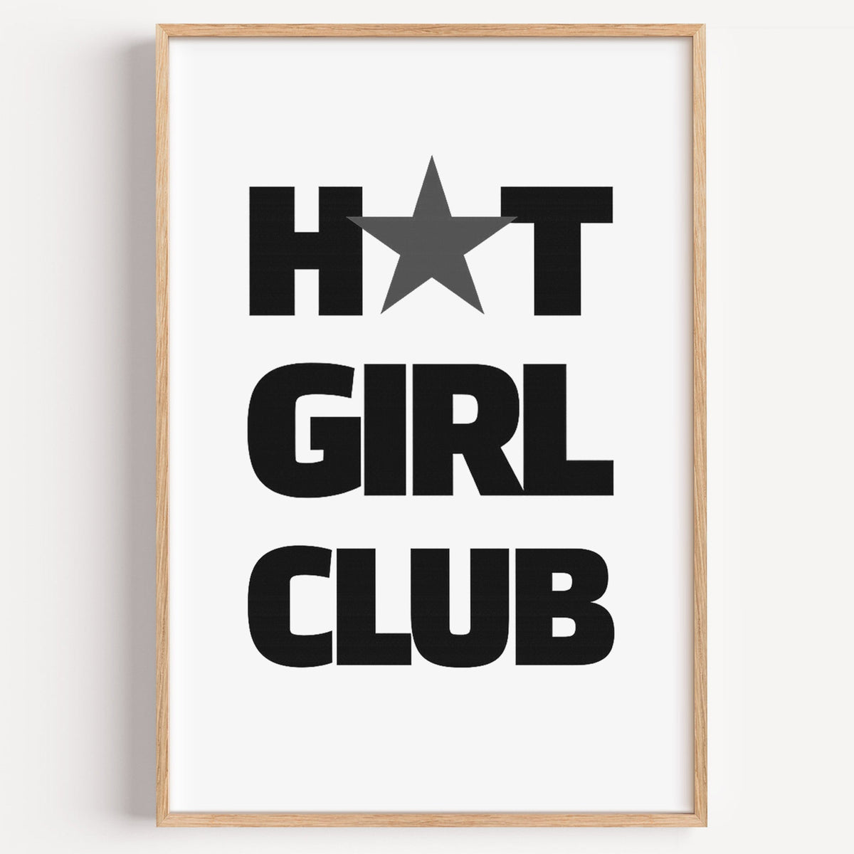 Bold Girl Club lettering with gray star print in a light oak frame on a plain white wall