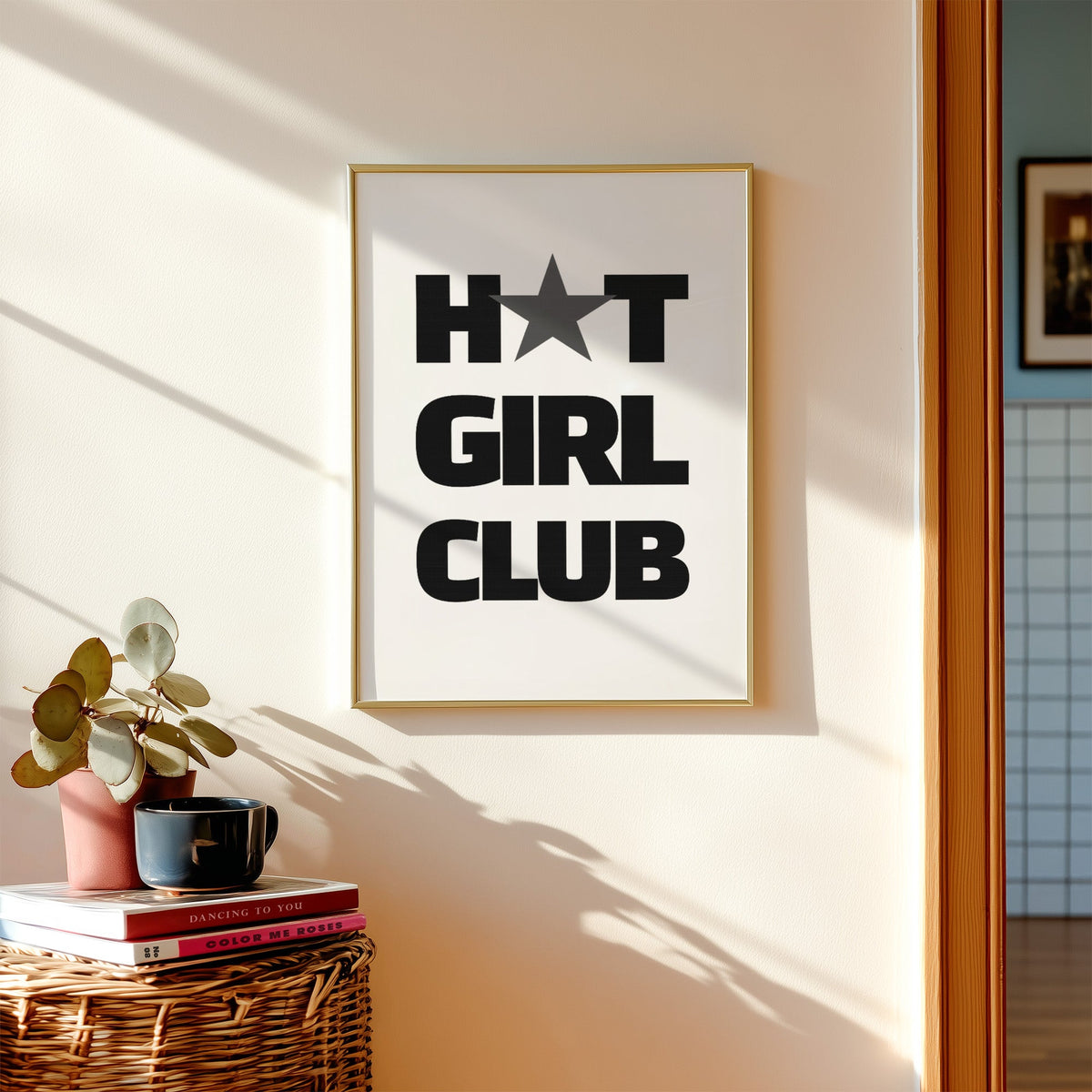 Bold Girl Club lettering with gray star print shown in a gold frame above a wicker basket and stacked books