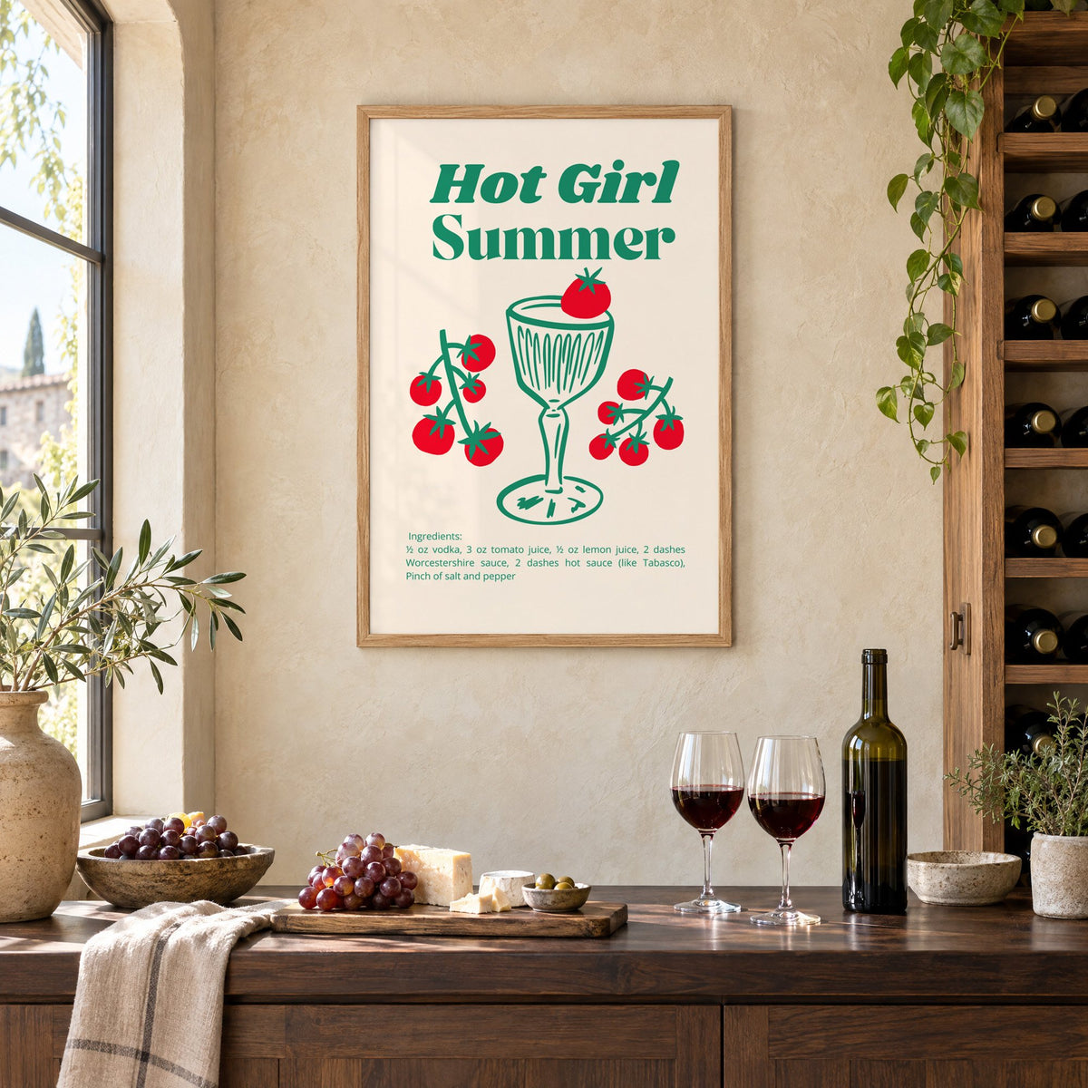 Hot Girl Summer tomato cocktail recipe print in an oak frame on a limewashed wall above a wine counter with red wine, cheese and grapes