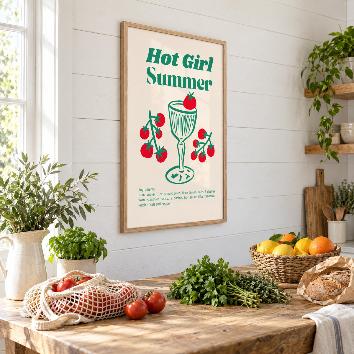 Hot Girl Summer tomato cocktail recipe print in an oak frame on a shiplap wall above a farm table with market tomatoes and citrus, seen at an angle