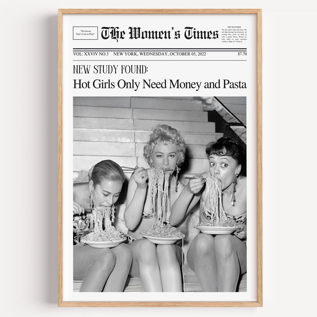 Three women eating spaghetti on stairs newspaper print in a light oak frame on a plain white wall
