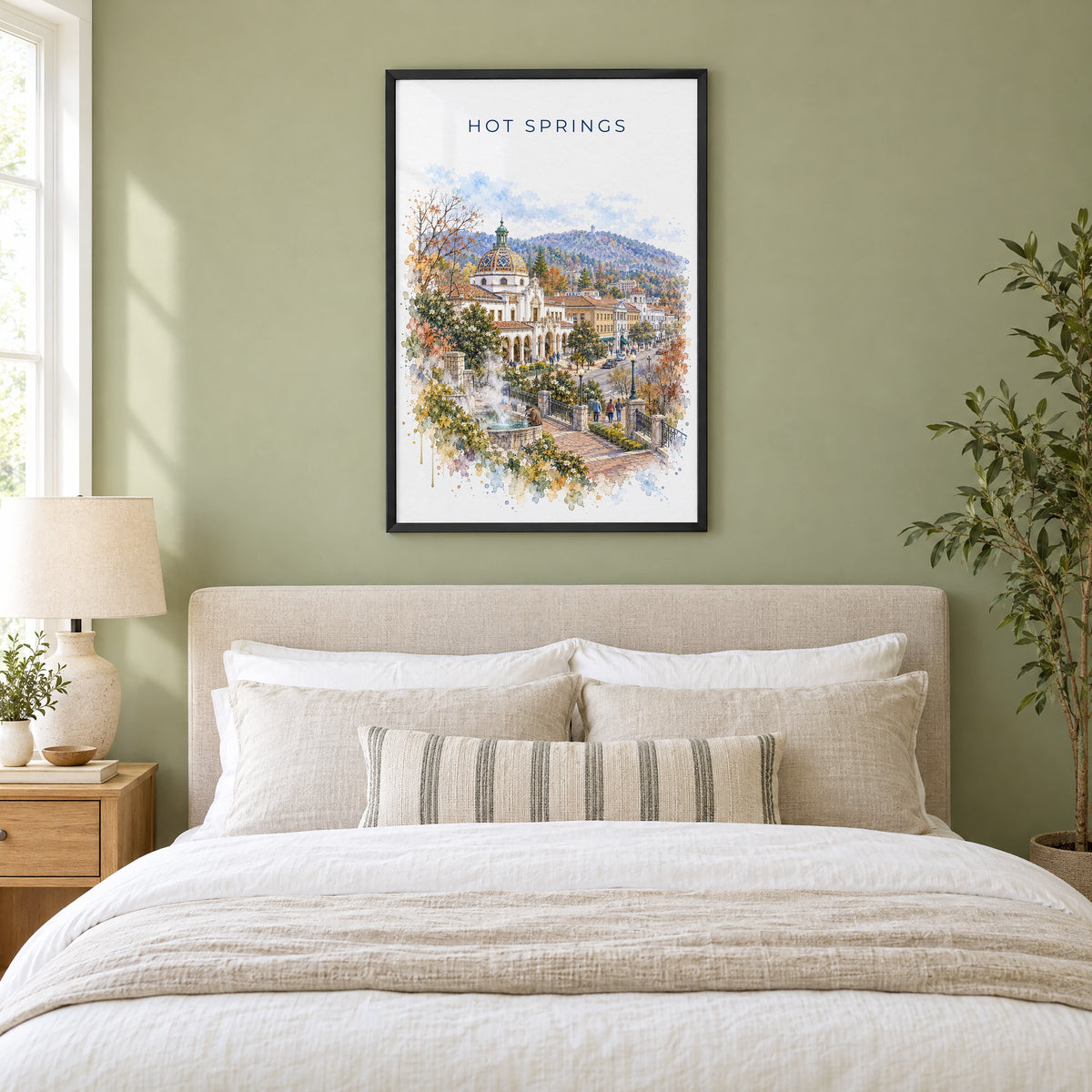 Hot Springs, Arkansas watercolor print in a black frame above an upholstered headboard in a sage green bedroom