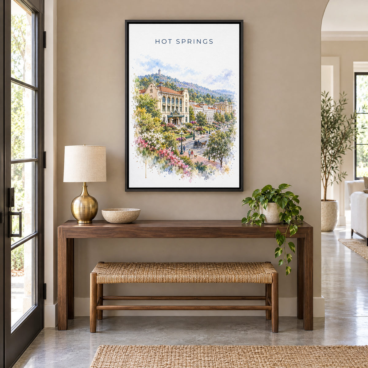Hot Springs National Park watercolor print as a black floater canvas above a walnut console and woven bench in an entryway