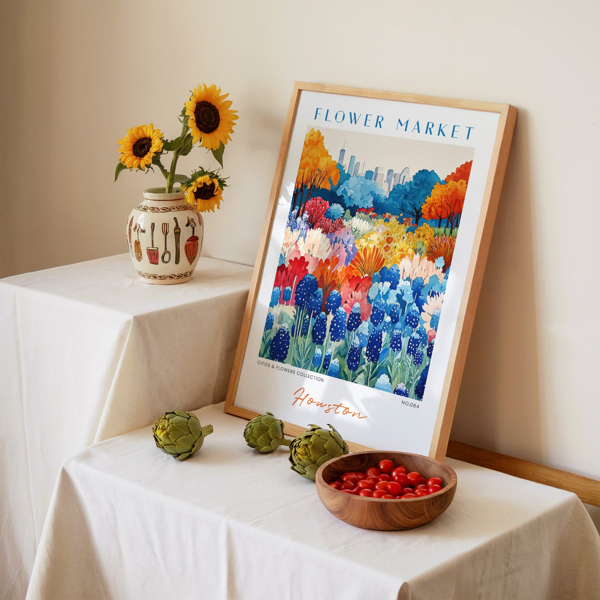 Houston flower market print in an oak frame leaning on a linen-draped table beside a vase of sunflowers