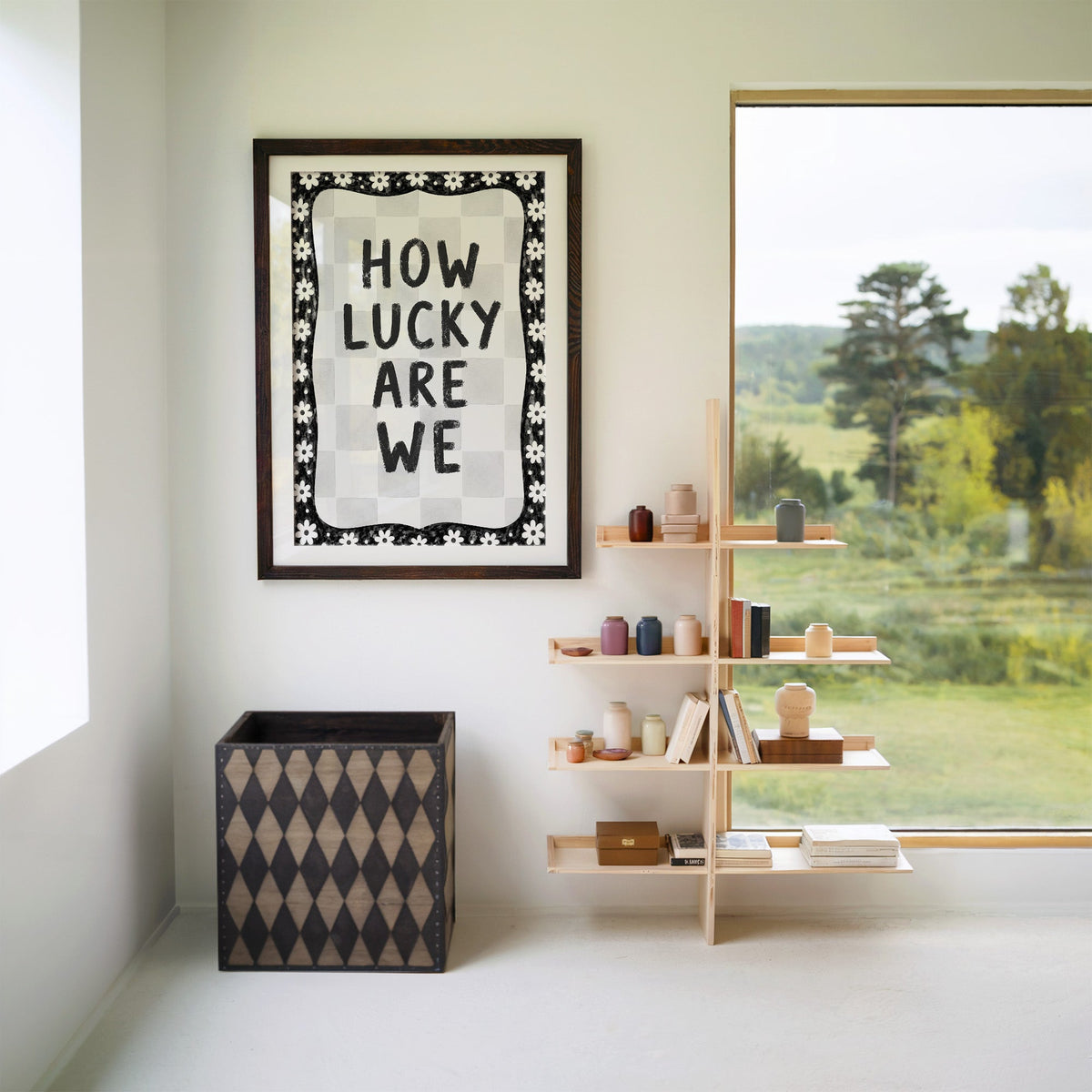 How lucky are we quote with white daisy border print in a walnut frame with a white mat beside wooden shelves and a garden window