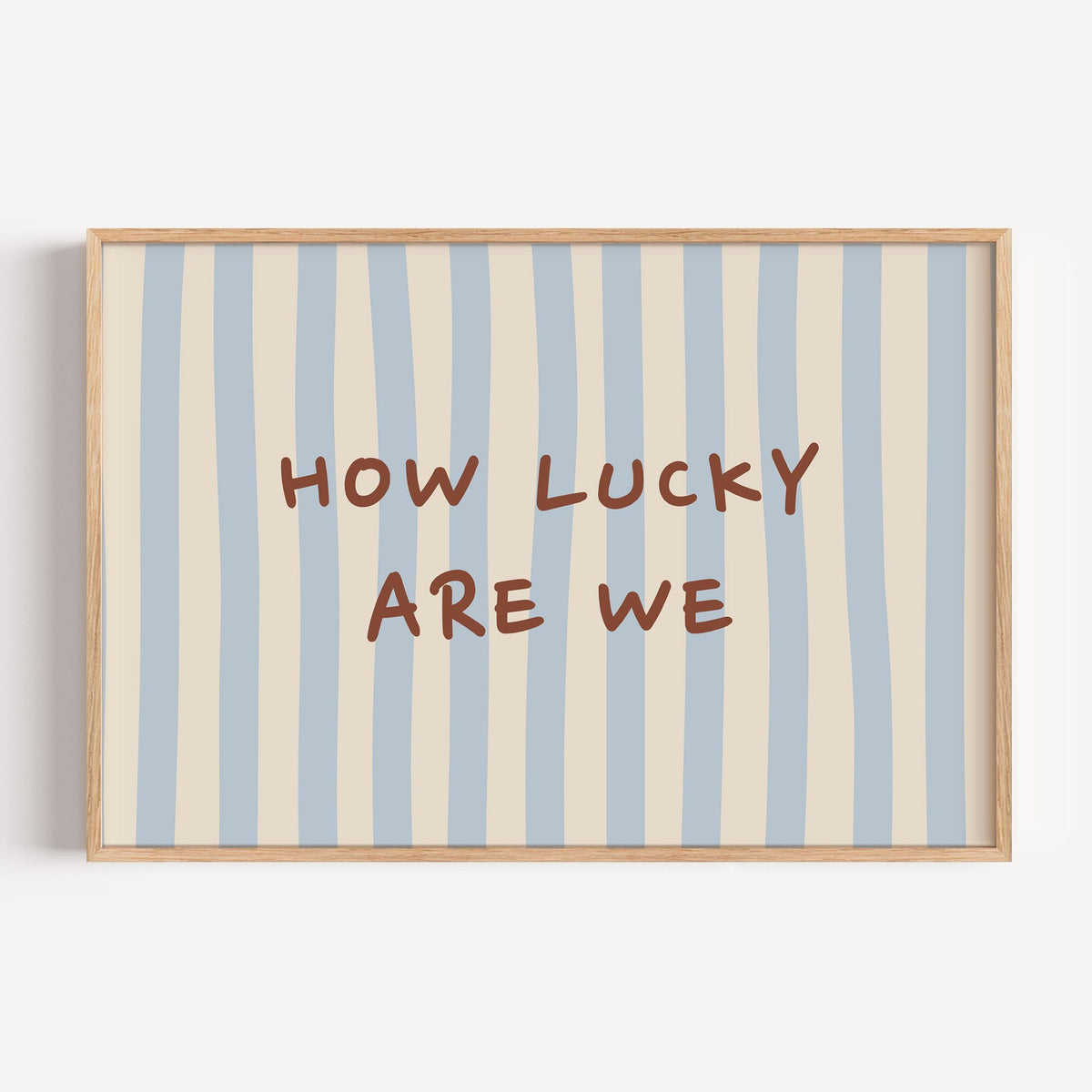 Landscape how lucky are we nursery print in a light oak frame on a plain white wall