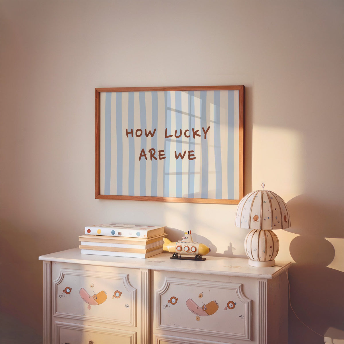 Landscape how lucky are we nursery print in a cherry wood frame above a painted dresser and lamp