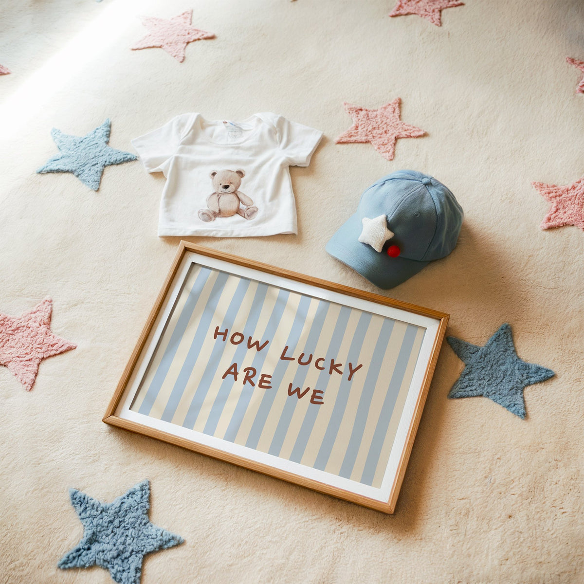 Landscape how lucky are we nursery print in a matted oak frame on a star rug with a baby tee