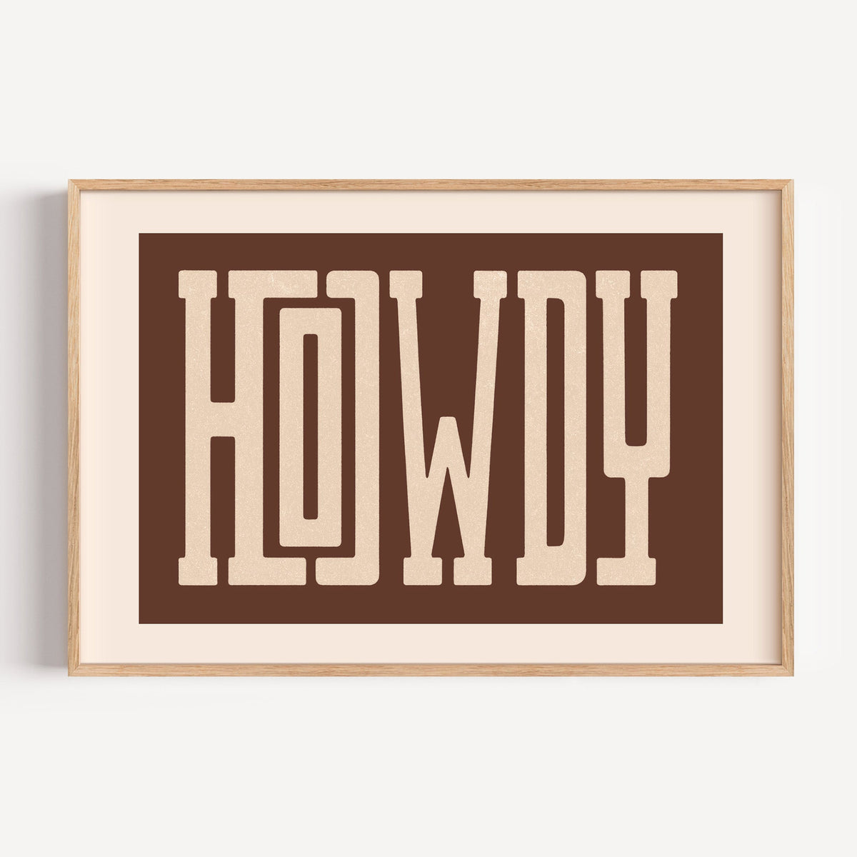 Howdy block letter banner print in a light oak frame on a plain white wall