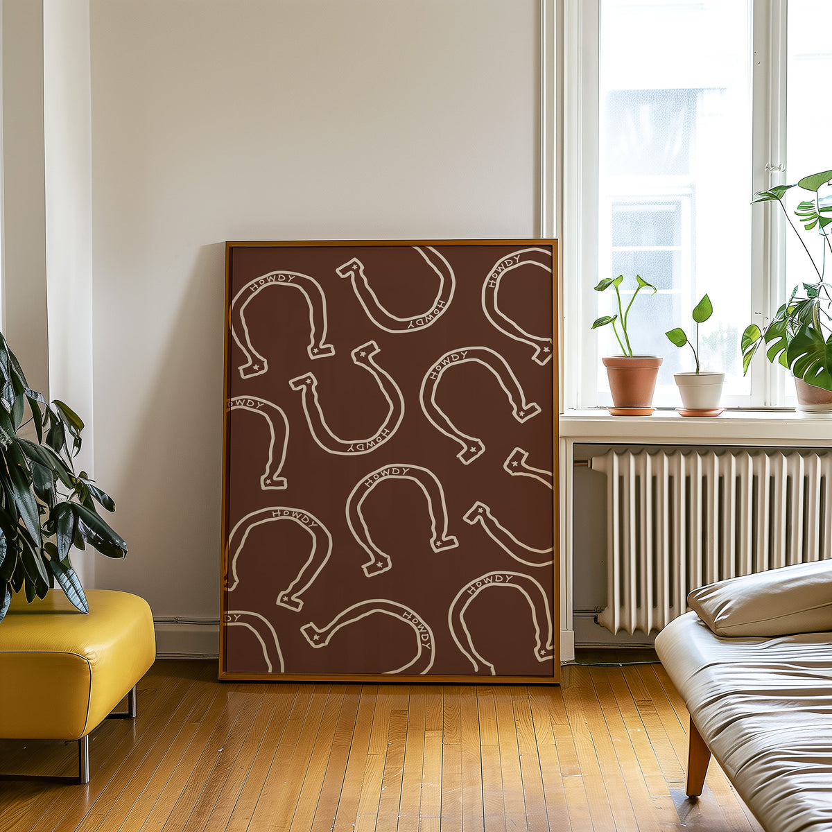 Howdy horseshoe brown pattern print in an oak frame on a parquet floor beside a yellow bench