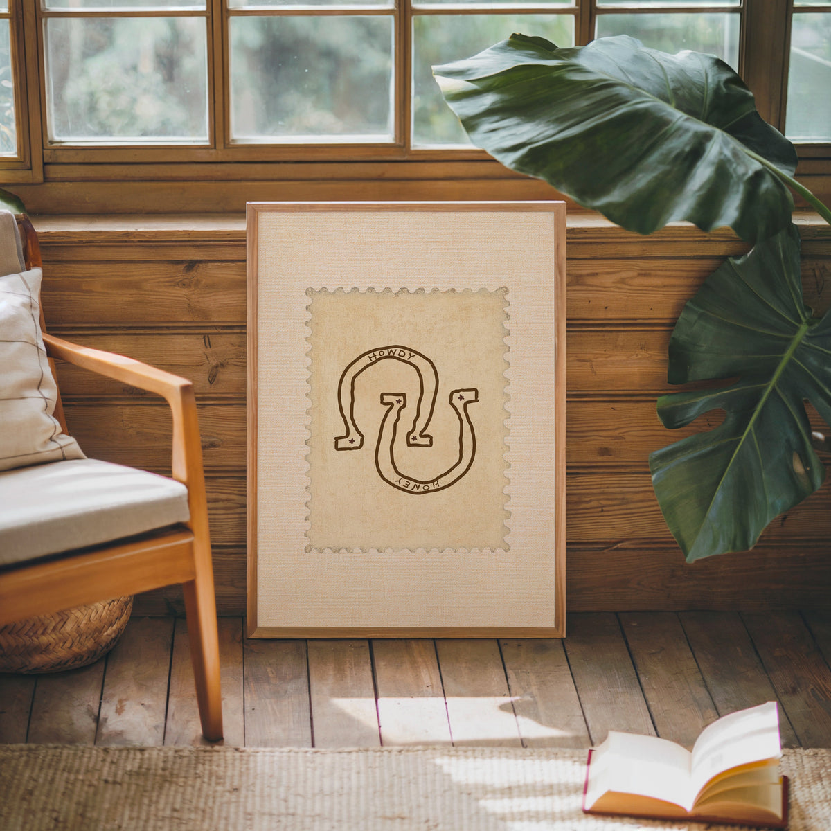 Howdy horseshoe cream stamp print in an oak frame against a wood panel cabin wall