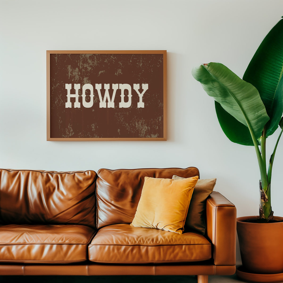 Howdy weathered brown print in an oak frame above a cognac leather sofa