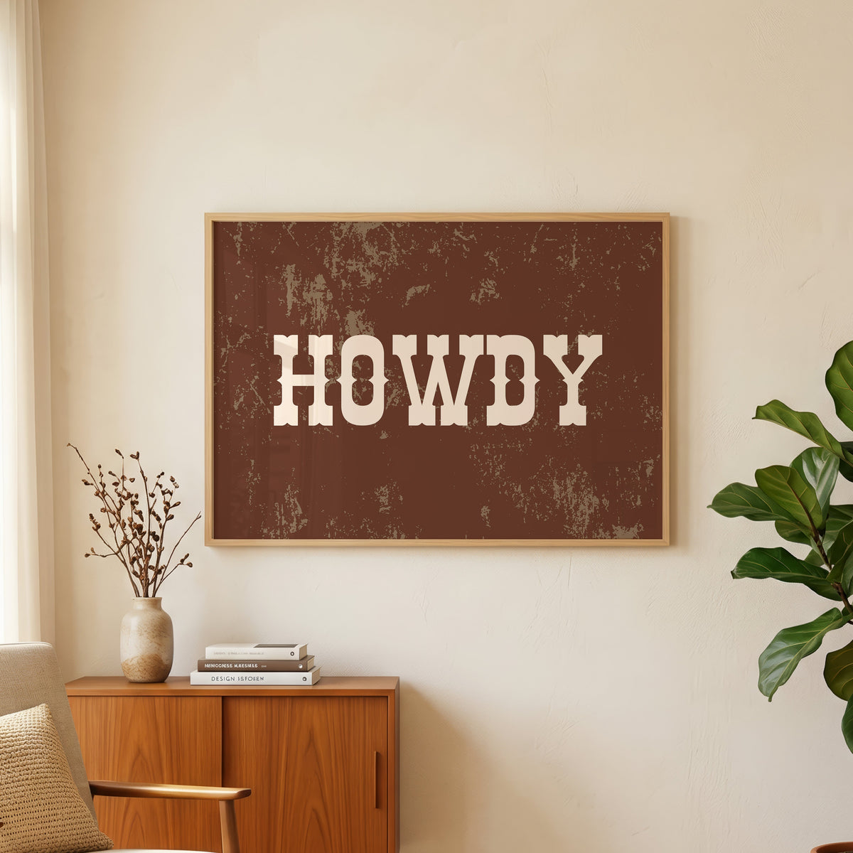 Howdy weathered brown print in an oak frame above a teak sideboard with a fig plant