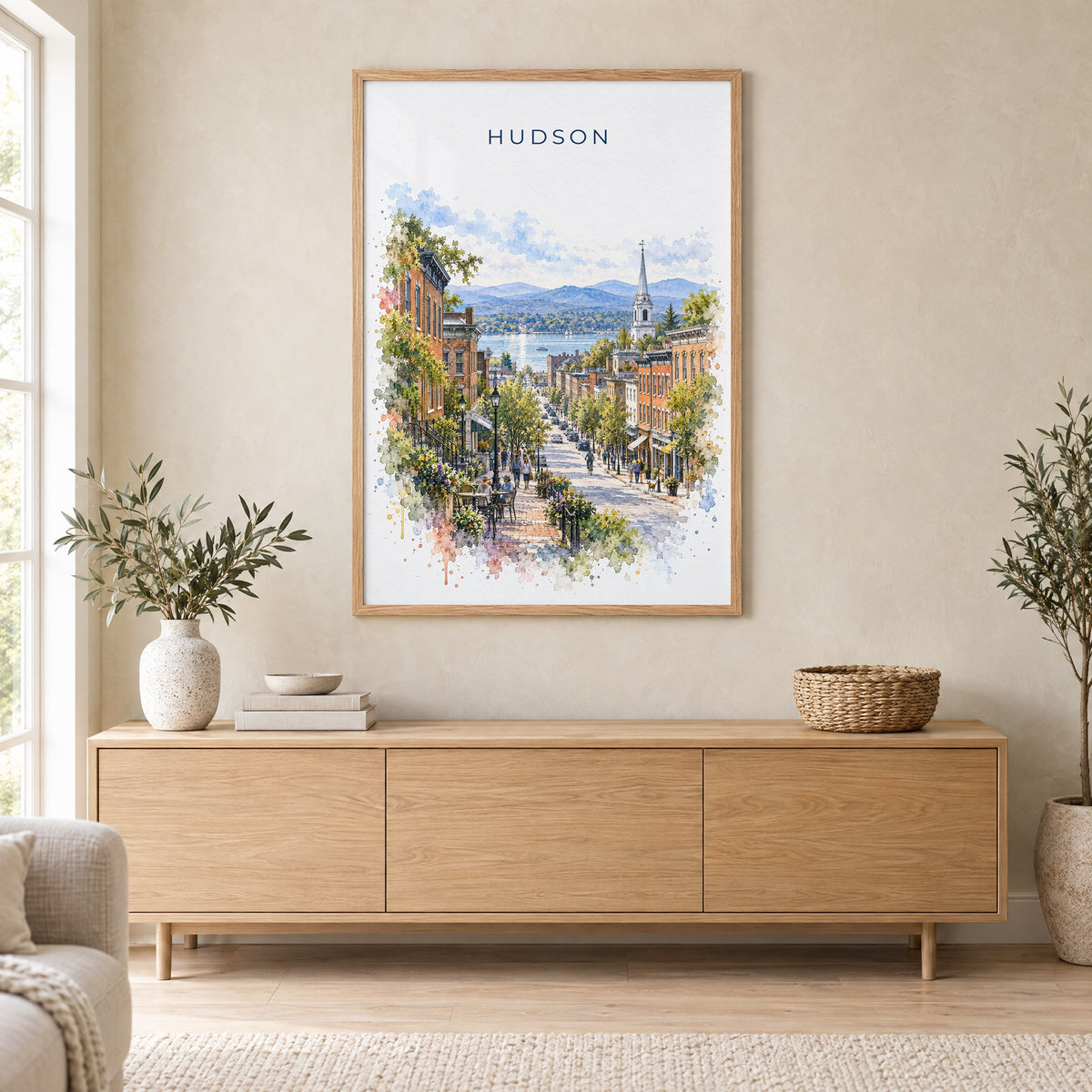 Hudson, New York watercolor print in an oak frame above a light wood sideboard in a Scandinavian living room