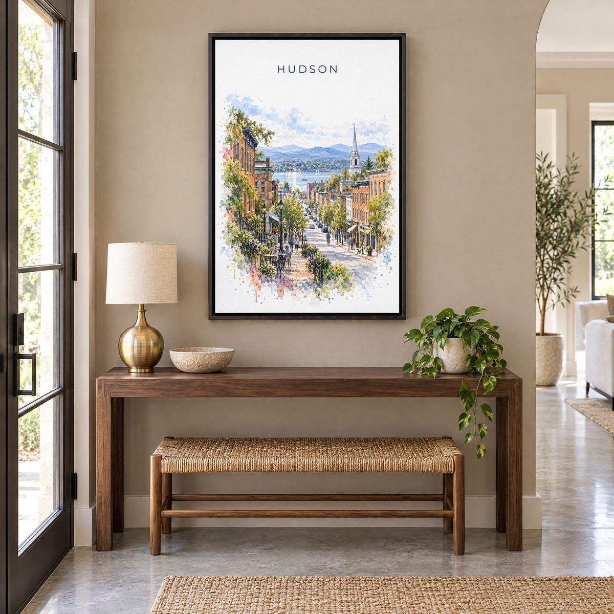 Hudson, New York watercolor print as a black floater canvas above a walnut console and woven bench in an entryway