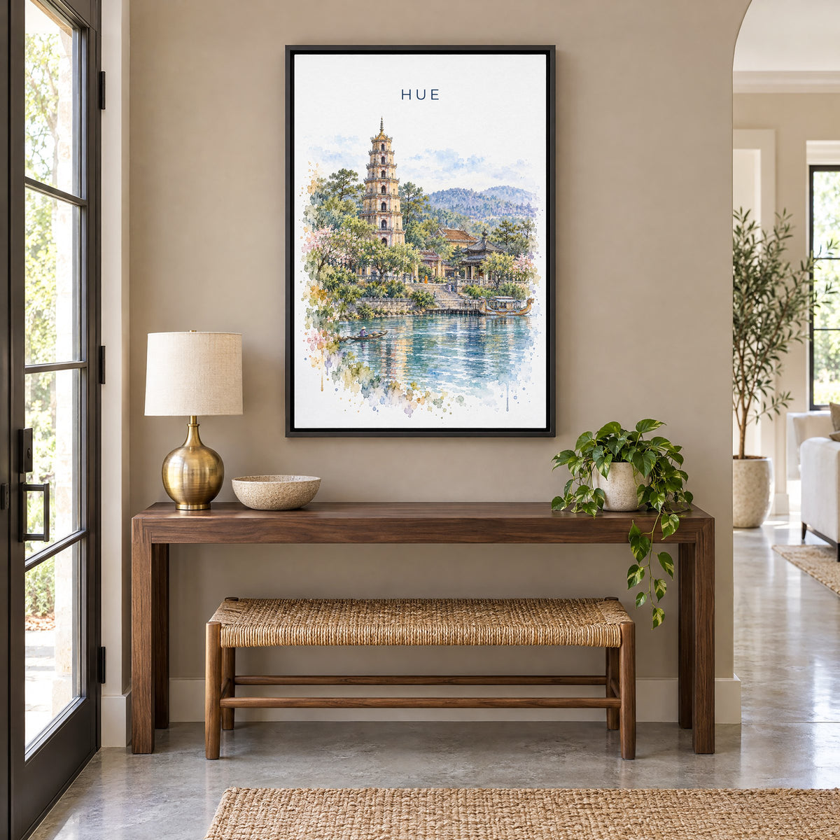 Hue, Vietnam watercolor print as a black floater canvas above a walnut console and woven bench in an entryway