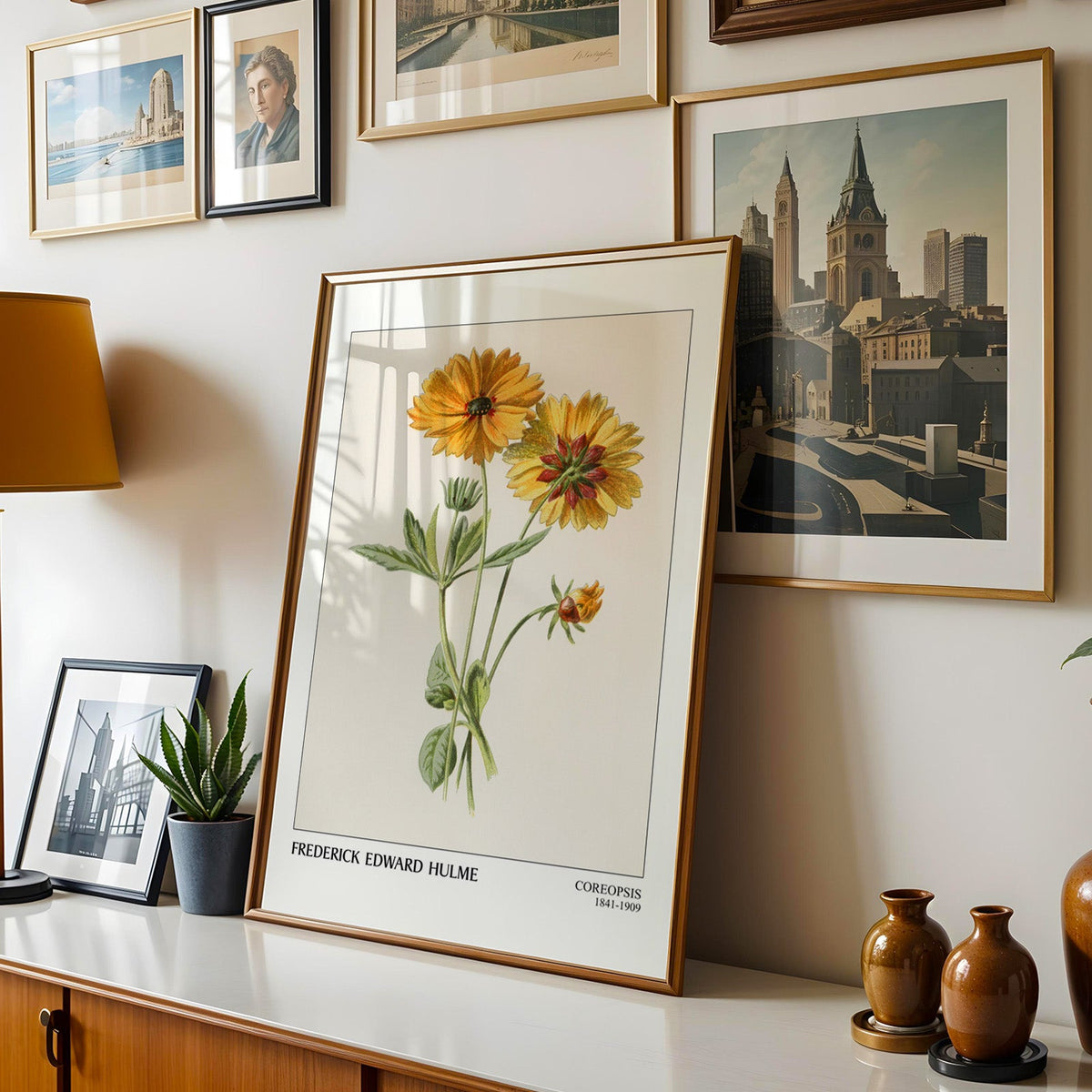 Flower plate shown in a gold frame leaning on a sideboard in a gallery wall