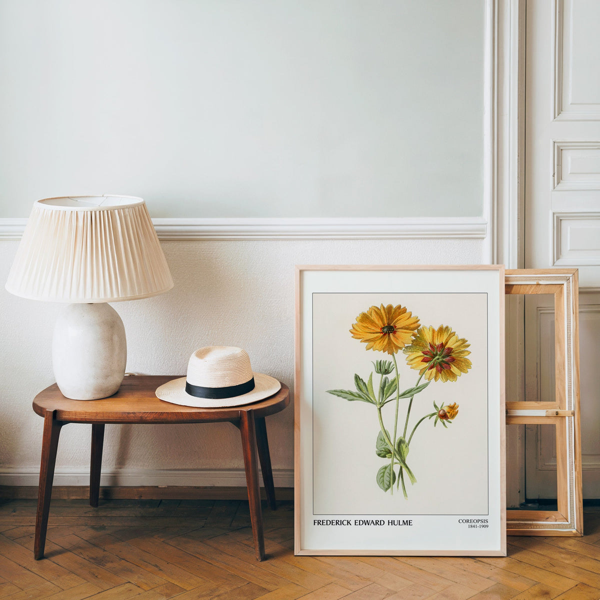 Vintage botanical poster in a light wood frame leaning by a bench and hat