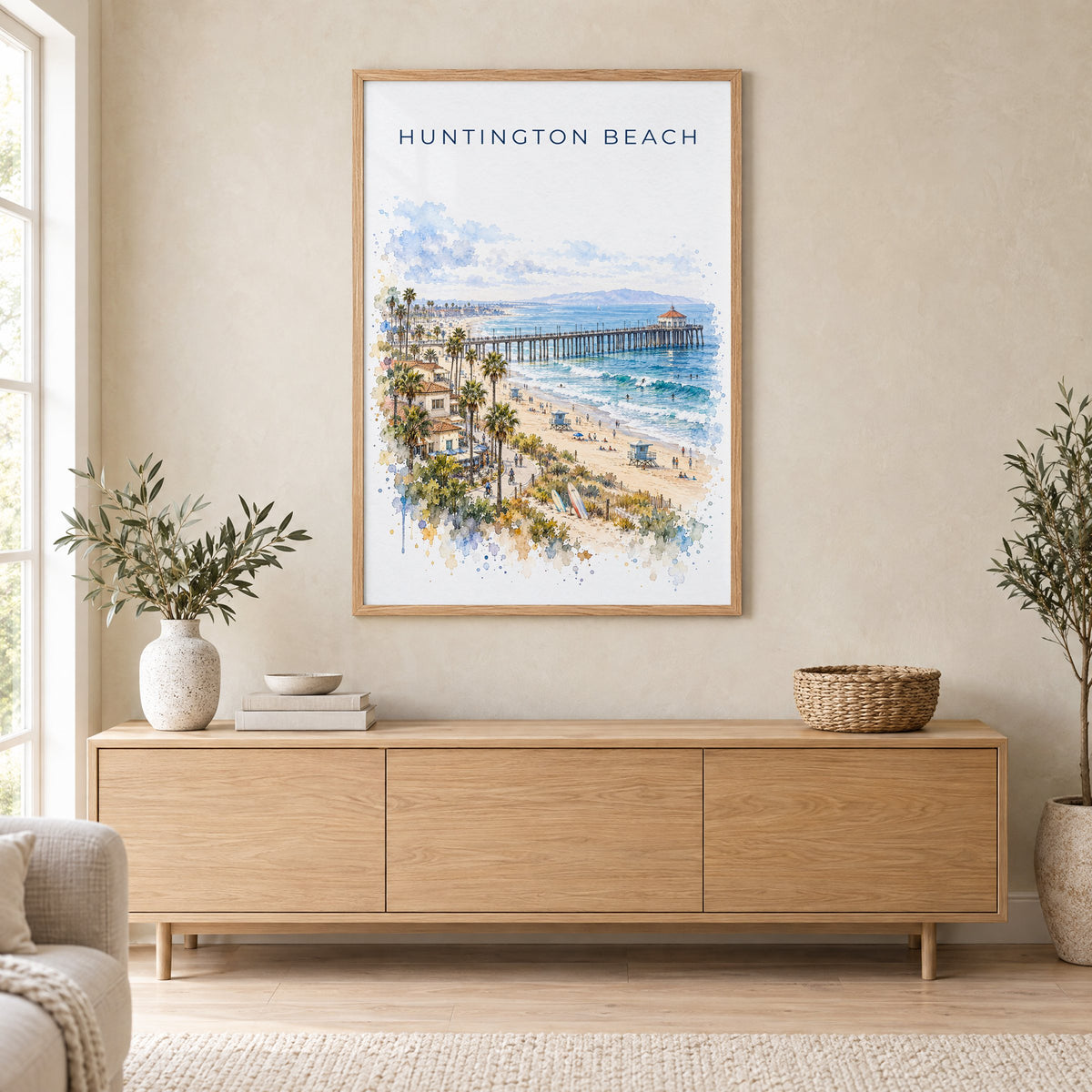 Huntington Beach watercolor print in an oak frame above a light wood sideboard in a Scandinavian living room