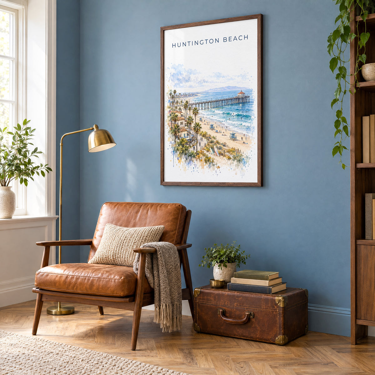 Huntington Beach watercolor print in a walnut frame on a blue wall above a leather armchair in a reading nook