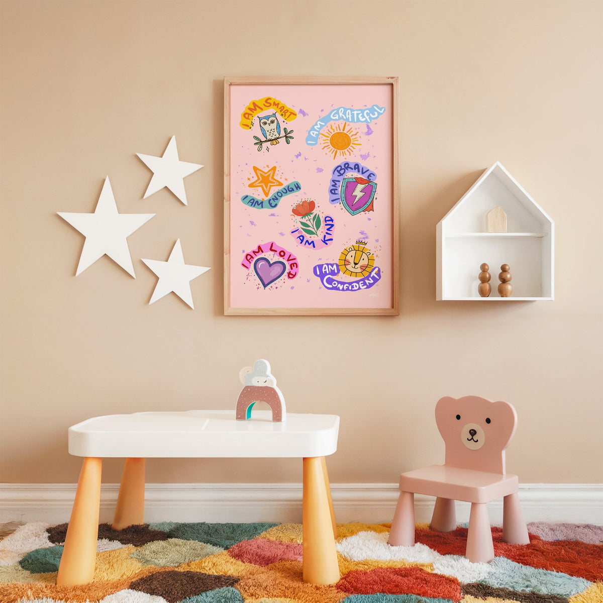 I am affirmations sticker nursery print in an oak frame on a peach wall above a kids table with wall stars