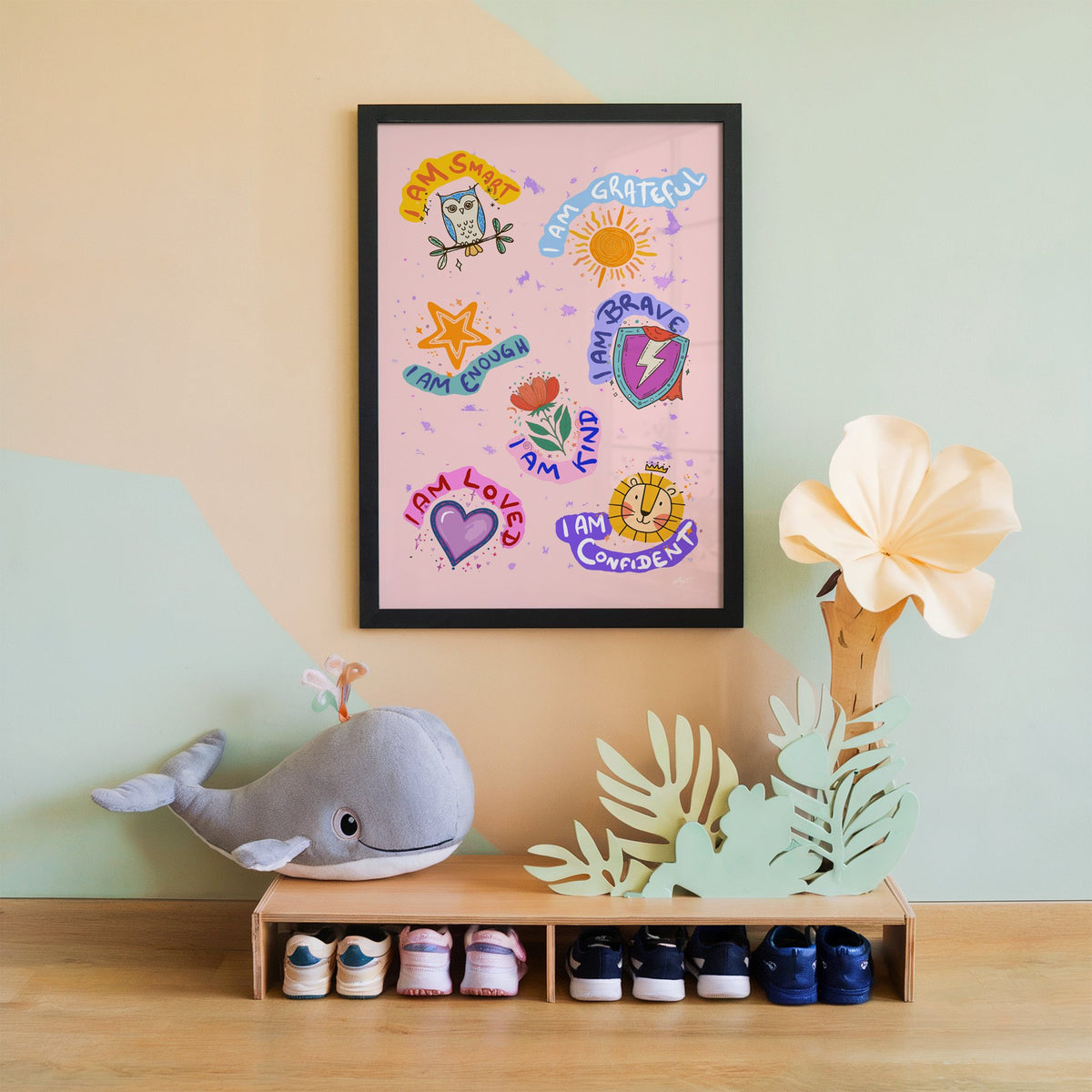 I am affirmations sticker nursery print in a black frame on a mint and peach wall above a whale plush